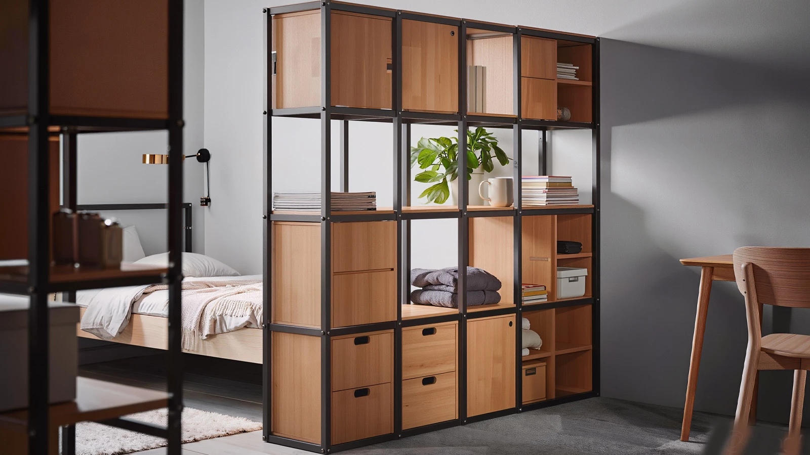 Modular open and closed shelving used as a room divider with storage in a compact 1-bedroom apartment shared living space.